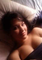 Клевая брюнетка лежит на кровати с голой грудью 1 фотография