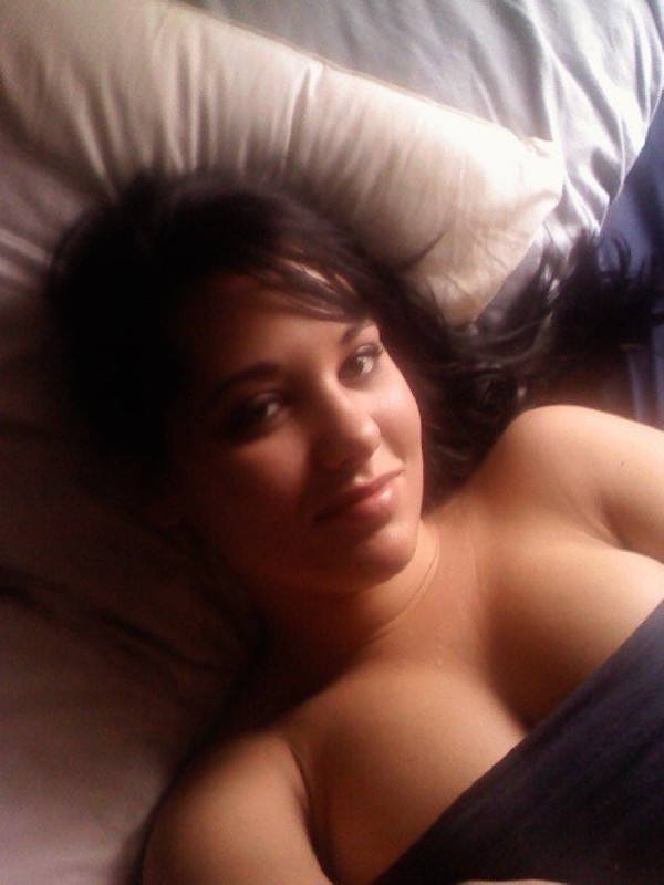 Клевая брюнетка лежит на кровати с голой грудью 1 фотография