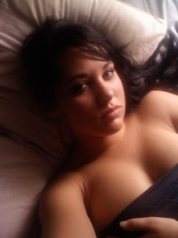 Клевая брюнетка лежит на кровати с голой грудью 2 фотография